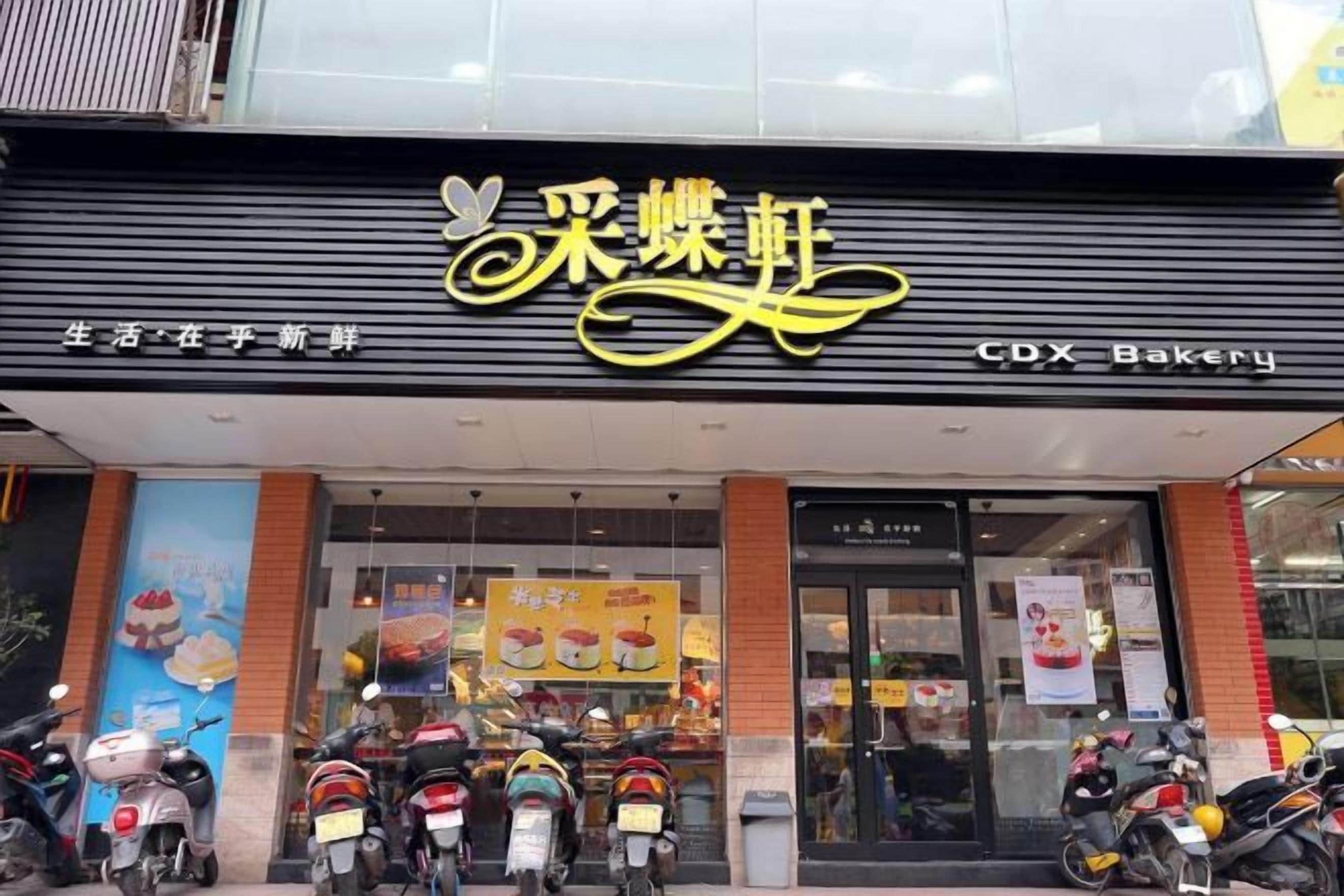 A storefront with a sign that reads 'Cdx Bakery' and a display of food items.