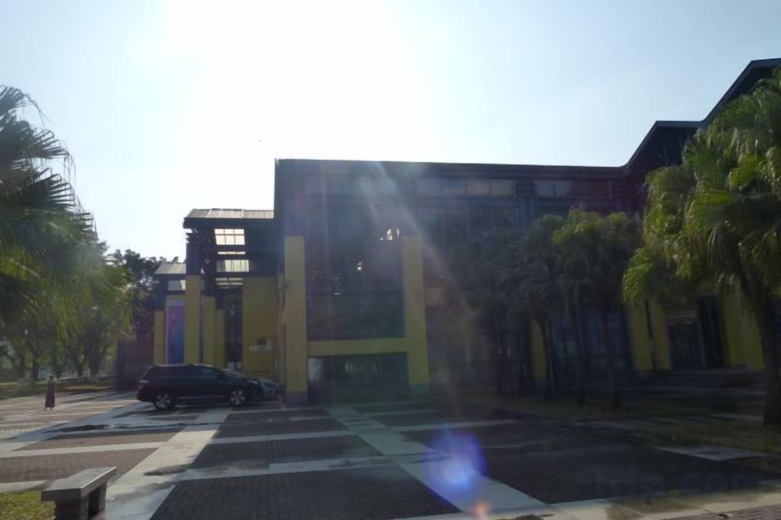 Un edificio dal design architettonico moderno, con un ingresso ben visibile e un'area di parcheggio.