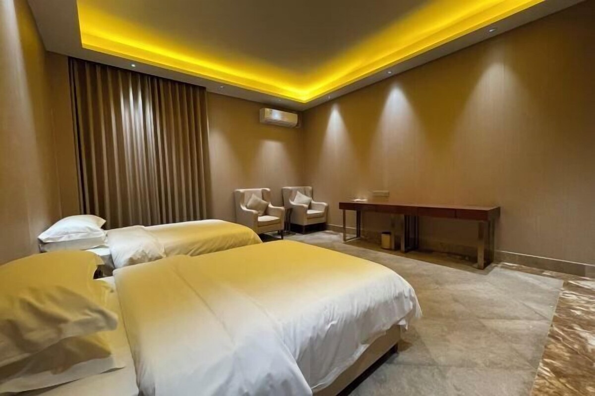 A hotel room with two beds, a desk, and a chair.