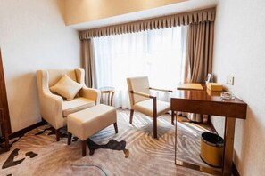 A hotel room with a sofa, armchair, small table, and a trash bin. - Fuyue Holiday Hotel(fuhua street store) (Zhongshan)