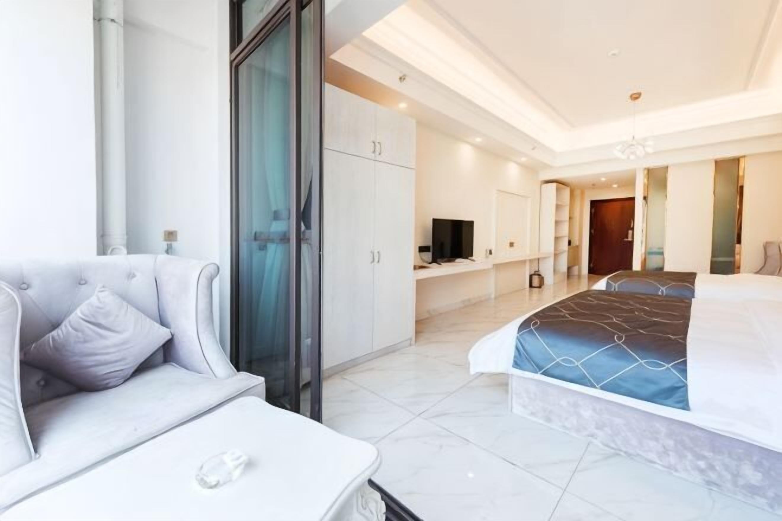 Una habitación de hotel moderna con cama, sofá, televisión y escritorio.