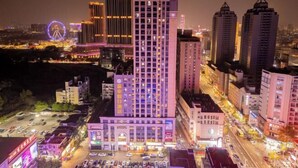Un grand hôtel à plusieurs étages, un parking et une grande roue en arrière-plan.