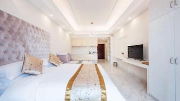 A modern hotel room with a large bed, a television, and a minibar.