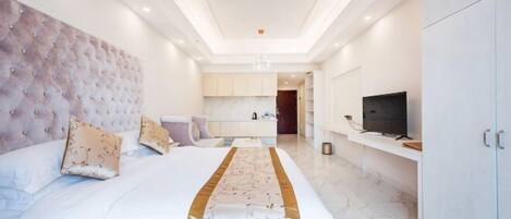 A modern hotel room with a large bed, a television, and a minibar.