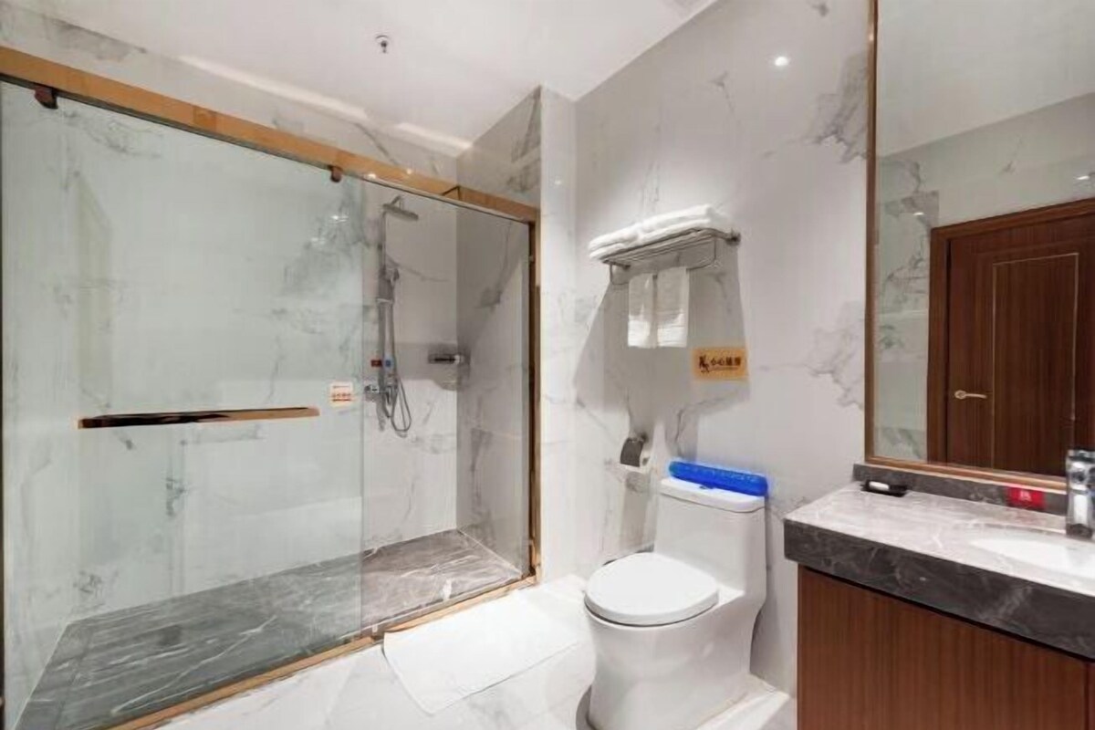 A bathroom with a glass-enclosed shower, a toilet, and a marble countertop.