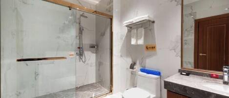 A bathroom with a glass-enclosed shower, a toilet, and a marble countertop.
