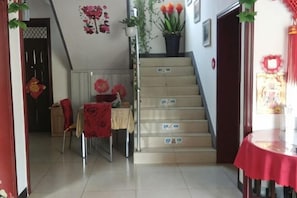 A staircase with a red table at the bottom, a chair, and a potted plant. - Beijing Simatai Xingyun Residence (Beijing)