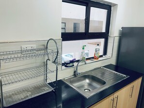 Kitchen features a stainless steel sink, black countertop, and wooden cabinets.
