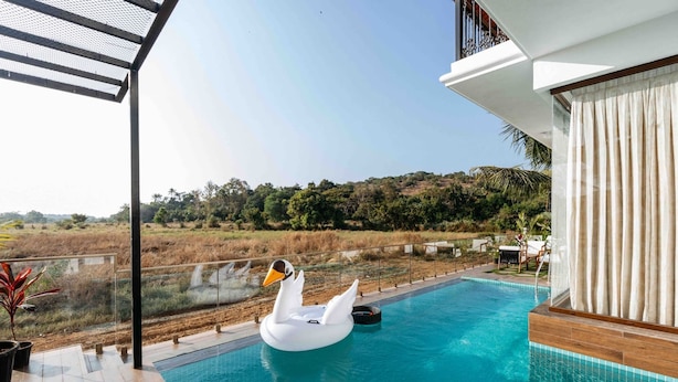 Ein Schwimmbecken mit einer Schwane als Schwimmgelegenheit, umgeben von einer Holzterrasse und einem weißen Gebäude mit Balkon.