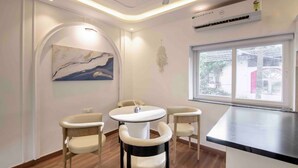 Een moderne kamer met een ronde tafel, vier stoelen, een plafondventilator, een airconditioning en een groot raam met uitzicht.