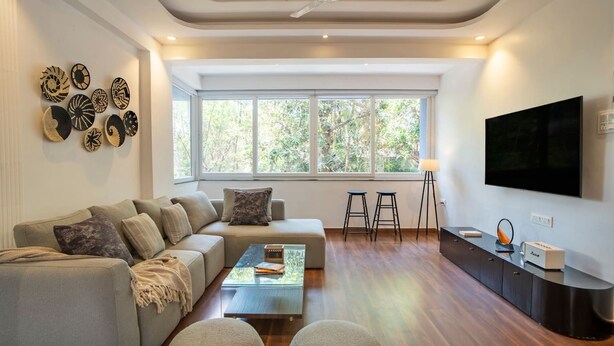 Een moderne woonkamer met een bank, salontafel en een aan de muur bevestigde televisie.