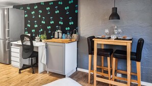 A compact kitchen with a refrigerator, a small sink, and a wooden dining table with black chairs.