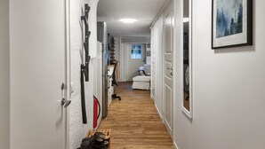 A narrow hallway with wooden flooring, white walls, and doors leading to various rooms.