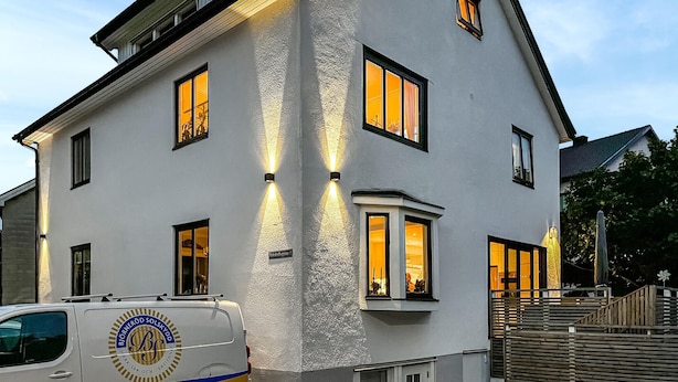 A white building with multiple windows and a van parked in front.
