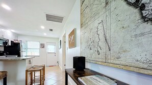 A modern kitchen with white cabinets, a black refrigerator, and a wooden dining table.