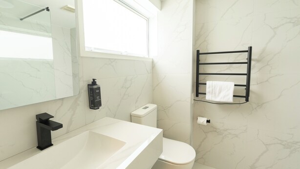 A modern bathroom with a white sink, black faucet, and a toilet. - Grand Riccarton Hotel (Christchurch)