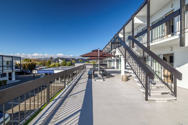 A hotel with a covered outdoor area, a staircase, and a view of the surrounding landscape. - Grand Riccarton Hotel (Christchurch)