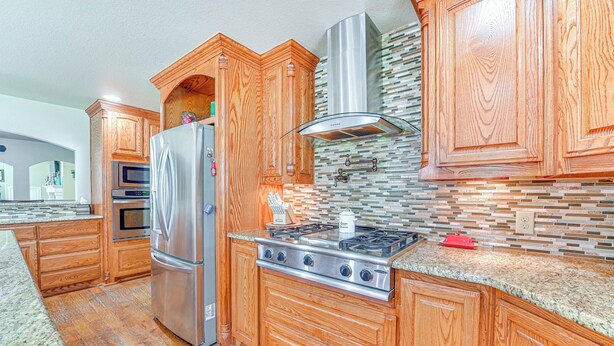 Una cocina con armarios de madera, un refrigerador de acero inoxidable, una estufa a gas y un microondas.
