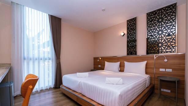 A hotel room with a large bed, a desk, a chair, and a decorative wall panel. - One Budget Hotel Nan Pha Sing (Nan)
