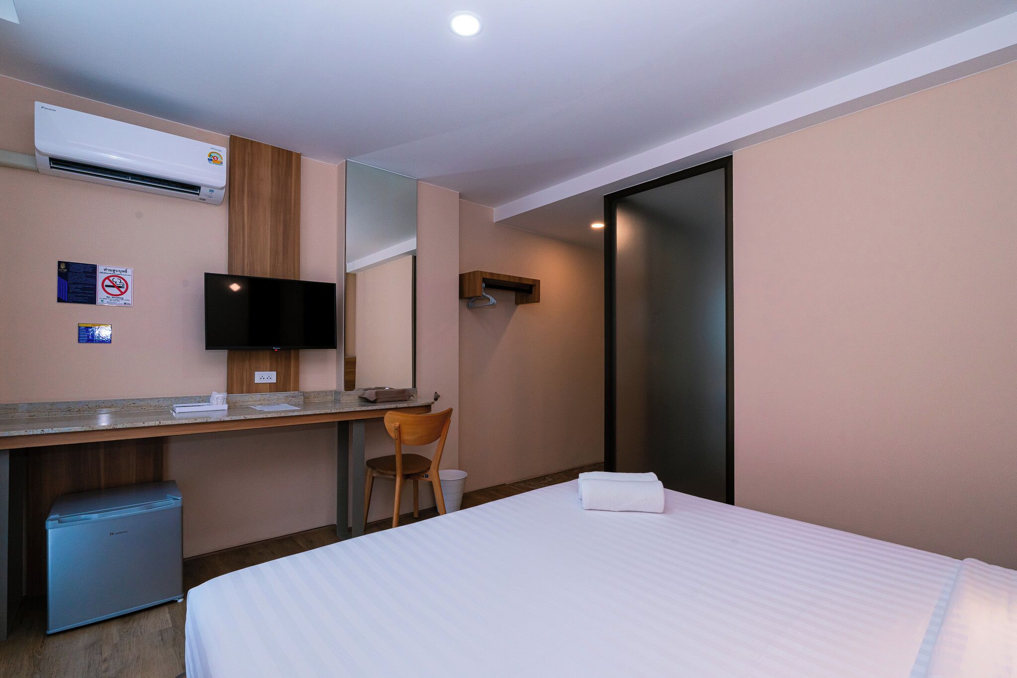 Une chambre d’hôtel équipée d’un lit, d’un bureau, d’une chaise, d’une télévision et d’un mini-bar.