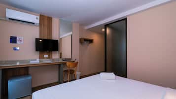 Une chambre d’hôtel équipée d’un lit, d’un bureau, d’une chaise, d’une télévision et d’un mini-bar.