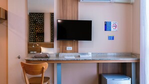 A hotel room with a flat-screen TV mounted on the wall, a wooden desk with a chair, a small trash bin, and a no-smoking sign. - One Budget Hotel Nan Pha Sing (Nan)