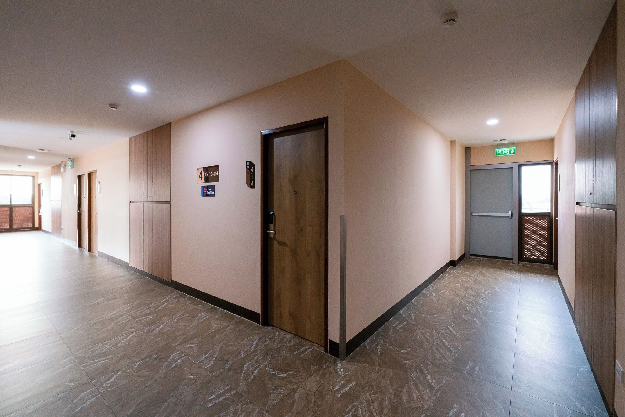 A hallway with a wooden door, a sign indicating room number 414, and a no-smoking sign.