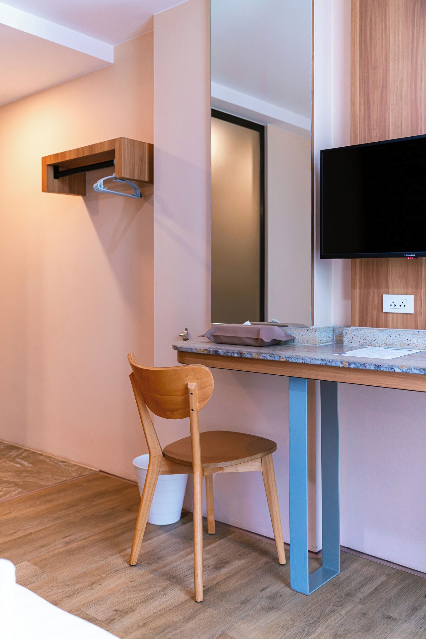 Une salle de bain moderne avec un meuble-lavabo en bois, un évier, un miroir et un téléviseur fixé au mur.