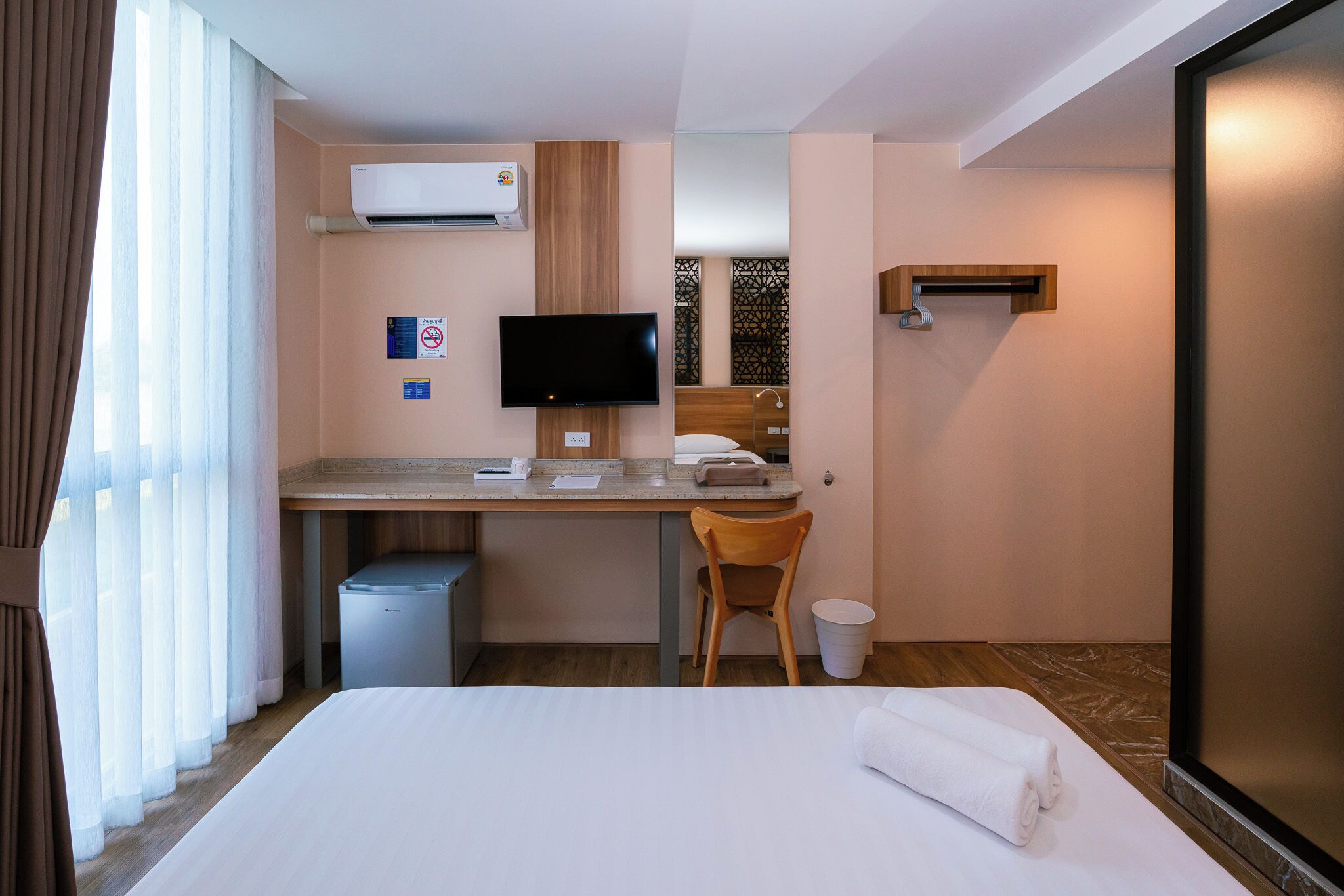 Ett hotellrum med en säng, ett skrivbord med en dator, en TV och en luftkonditioneringsanläggning.