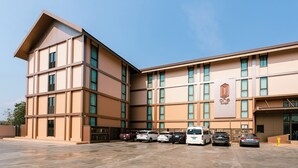 A multi-story hotel with a modern design, featuring a prominent logo on the facade. - One Budget Hotel Nan Pha Sing (Nan)