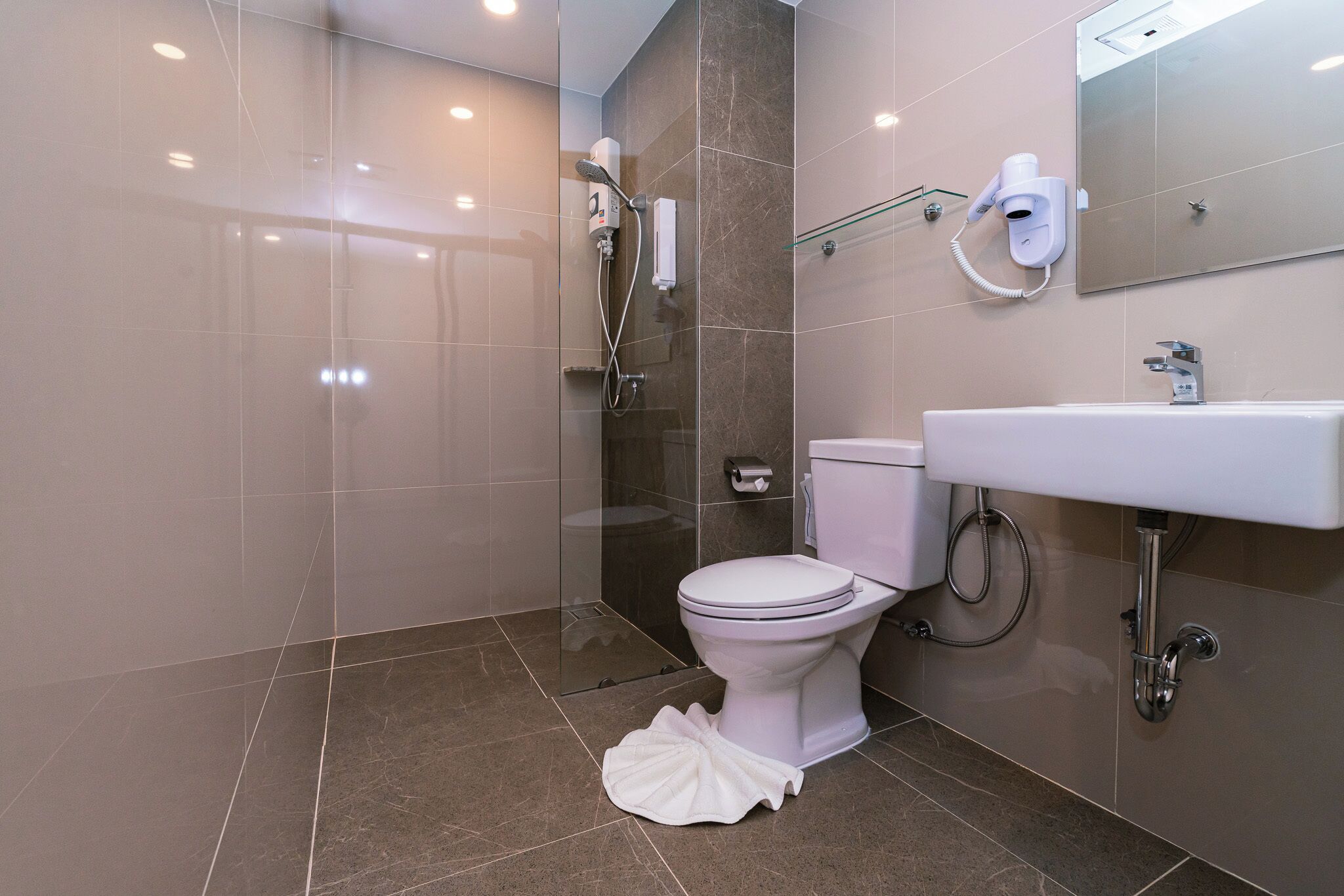 A modern bathroom with a toilet, bidet, and a glass shower enclosure.