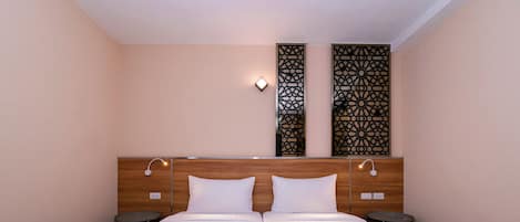 Una cama doble con ropa de cama blanca, dos mesitas de noche y paneles decorativos en la pared.