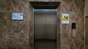 An elevator with a marble wall, emergency exit map, and a digital control panel. - One Budget Hotel Nan Pha Sing (Nan)