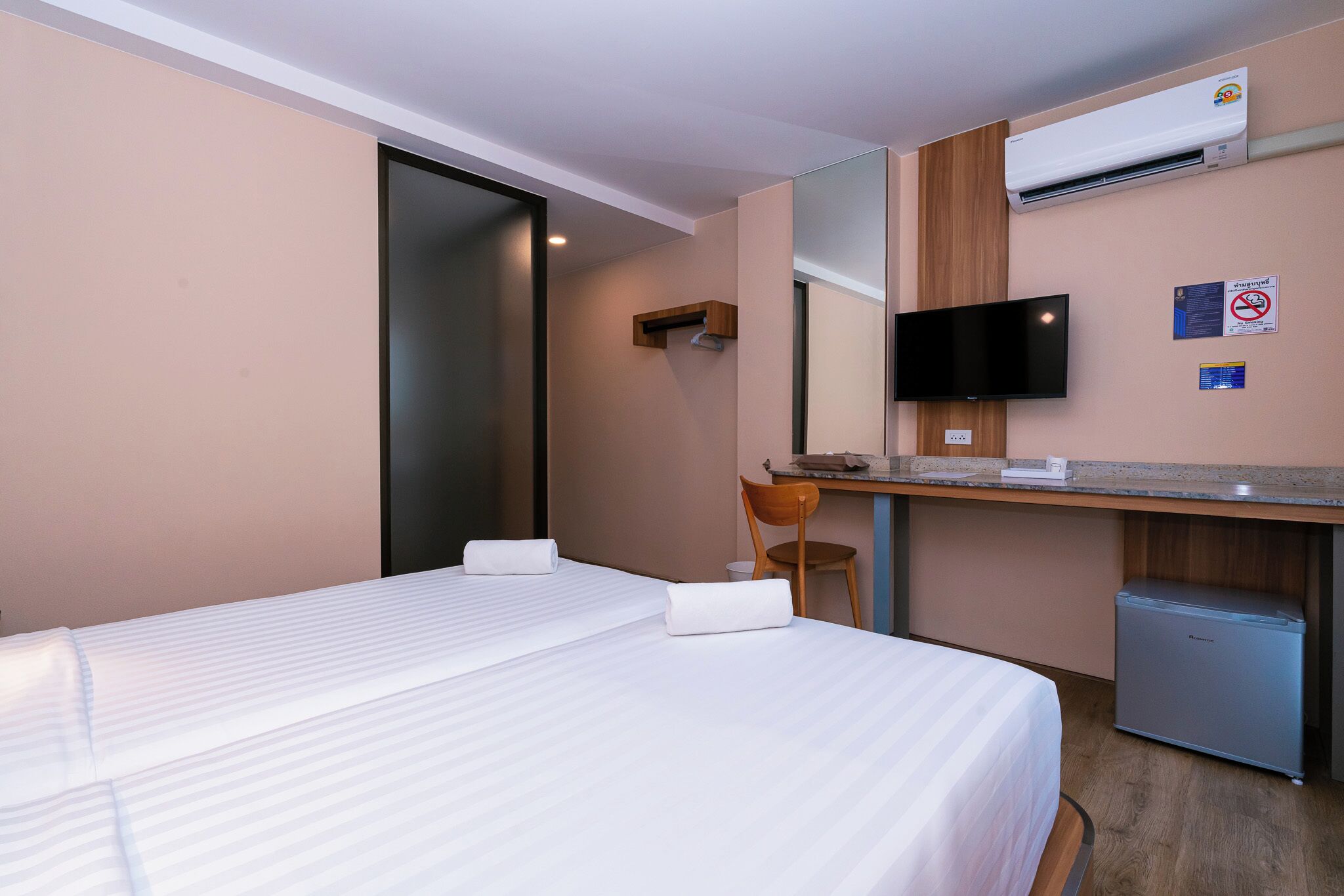 A hotel room with a bed, a desk, a chair, a television, and a small refrigerator.
