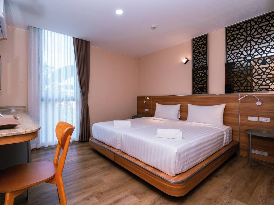 Habitación de hotel con cama, escritorio, silla y un panel decorativo en la pared.