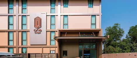 A building with a prominent 'one budget' sign, a covered entrance, and a parking area with cars and motorcycles.