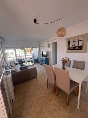 A modern living room with a dining area, a sofa set, a TV, and a painting on the wall.