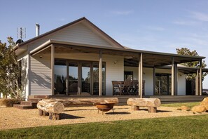 A modern house with a covered porch, large windows, and a gravel driveway. - Carrajung Estate (Willung South)