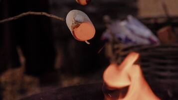 Two marshmallows roasting over a campfire.