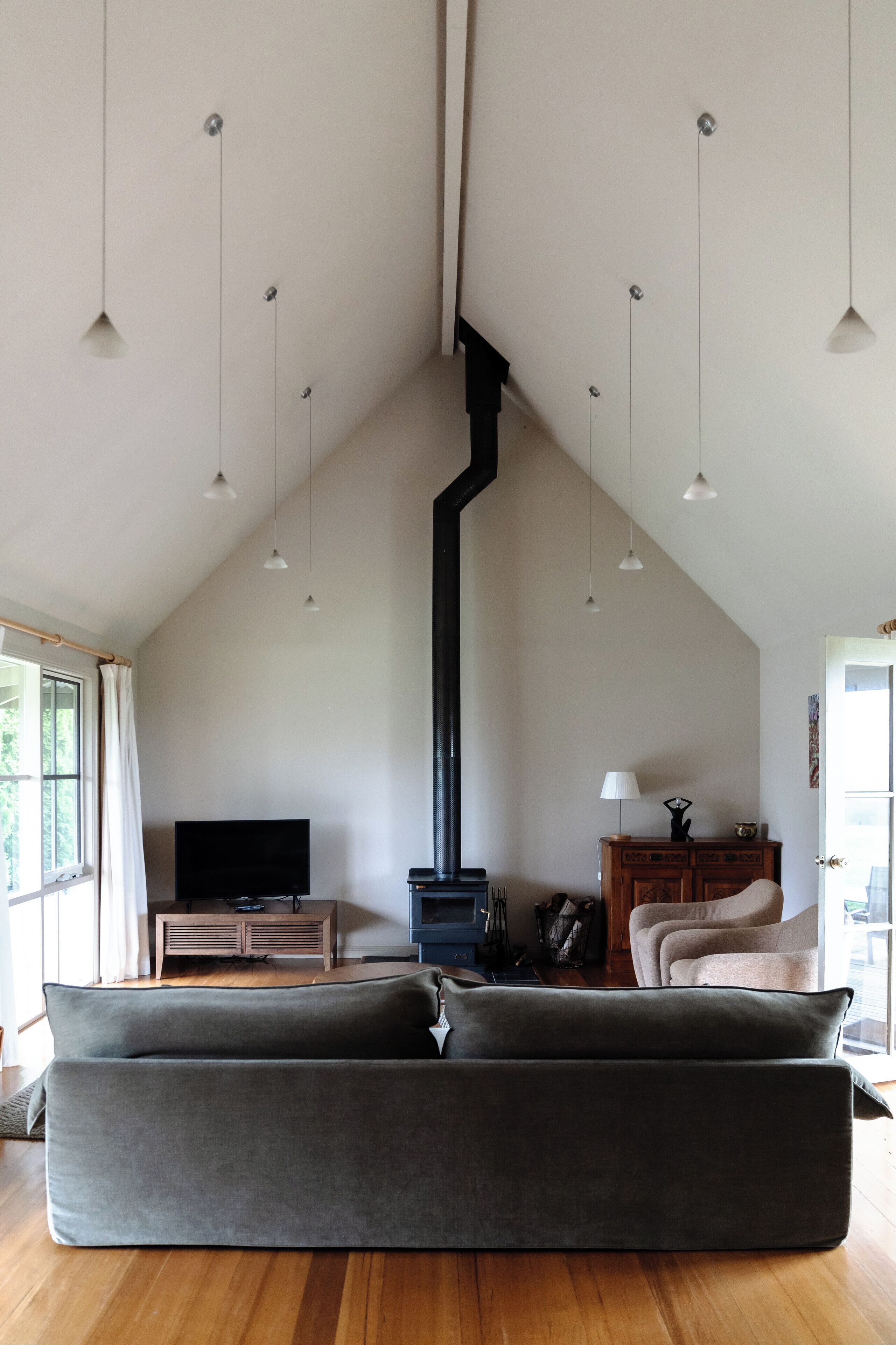 Una sala de estar con techo alto, chimenea, sofá e iluminación colgante.