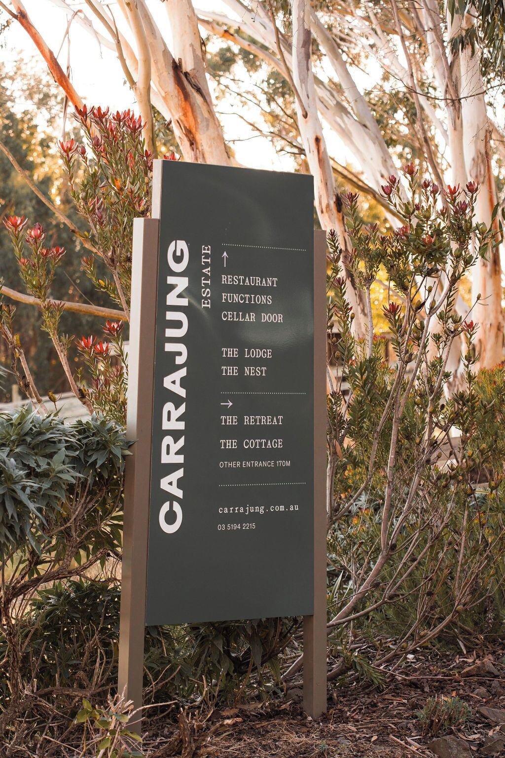 A sign listing the functions of Carrara Lodge, including a restaurant, cellar door, and various accommodations like The Lodge, The Nest, The Retreat, and The Cottage.