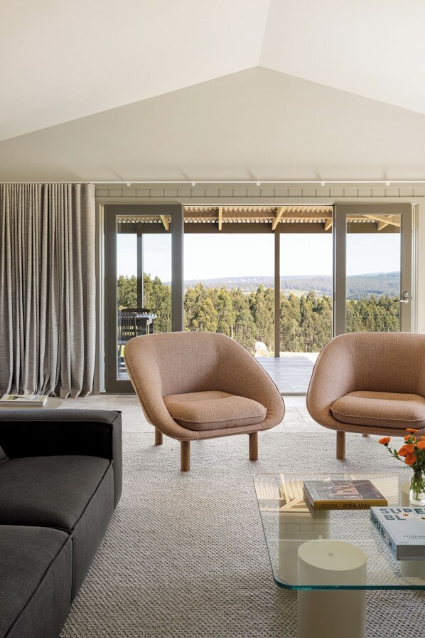 Una sala de estar moderna con dos sillones, un sofá y una mesa de centro de vidrio.