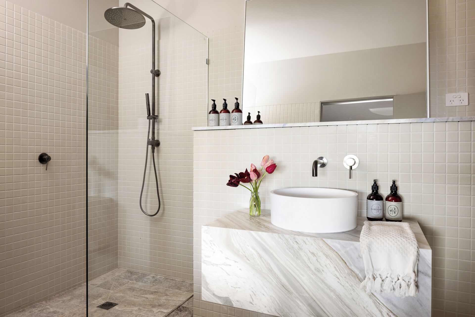 A bathroom with a shower, a sink, and a mirror.