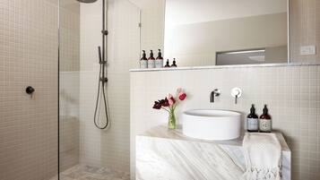 A bathroom with a shower, a sink, and a mirror.
