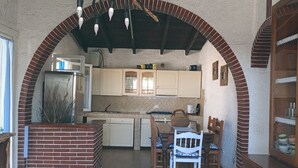 Une cuisine avec une arche en briques, des meubles blancs et un luminaire suspendu.