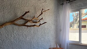 Une chambre à coucher avec un lit, une table de chevet en bois, une décoration murale en forme de branche et une fenêtre avec des rideaux.