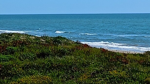 Un paysage côtier avec un ciel dégagé et des vagues sur l’océan.
