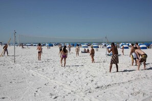 A beach volleyball court with players and spectators.