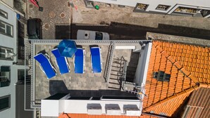 An aerial view of a rooftop with blue lounge chairs, a staircase, and a red-tiled roof. - Q Studios 2 by Atlantic Holiday (Funchal)
