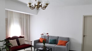 A living room with a red sofa, a grey sofa with colorful cushions, a small table, and a potted plant.